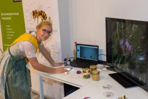 Die Bayerische Vize-Honigkönigin Laura platziert eine Bienenprobe unter dem Mikroskop am Stand der Landwirtschaftlichen Lehranstalten Triesdorf.