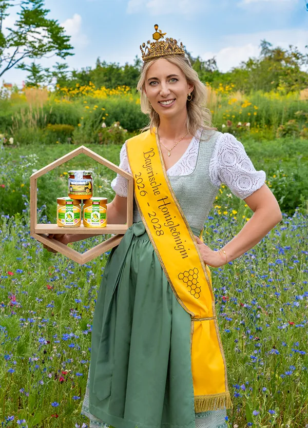 Frau mit Schärpe und Krone. Hält Honiggläser in der Hand