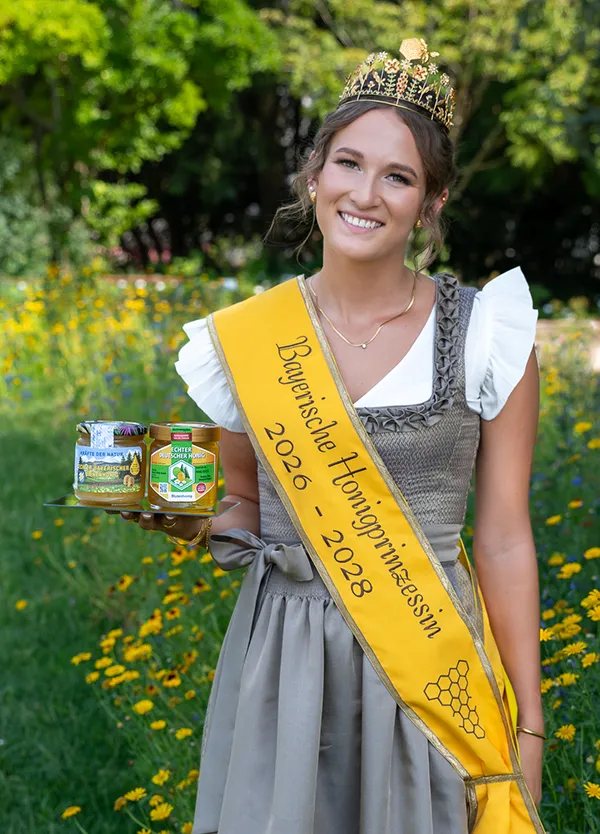 Frau mit Schärpe und Krone. Hält ein Honigglas in der Hand